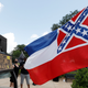 A Mississippi state flag waves adjacent to a flag change supporter’s sign that welcomes the state to “the right side of history,” outside the Capitol in Jackson, Miss., Sunday, June 28, 2020.